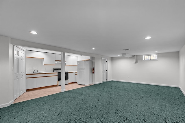 basement featuring sink, white fridge, and light colored carpet