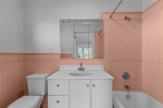 full bathroom featuring vanity, tiled shower / bath combo, tile walls, and toilet