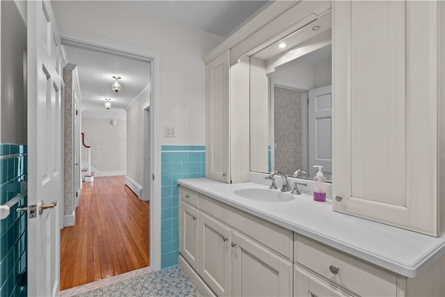 bathroom with wood-type flooring, vanity, and tile walls