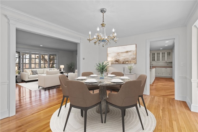 dining room featuring an inviting chandelier, ornamental molding, and light hardwood / wood-style flooring