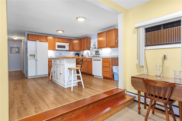 kitchen with a kitchen bar, white appliances, light hardwood / wood-style floors, and a baseboard radiator