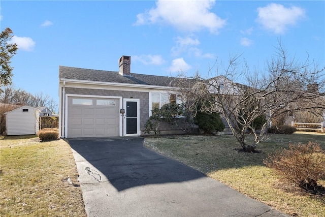 view of front of house with a garage, a front yard, and a storage shed