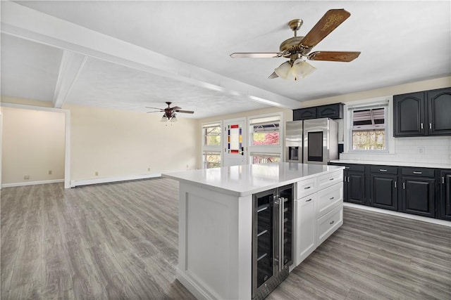 kitchen with a baseboard heating unit, beam ceiling, light hardwood / wood-style floors, stainless steel fridge with ice dispenser, and beverage cooler