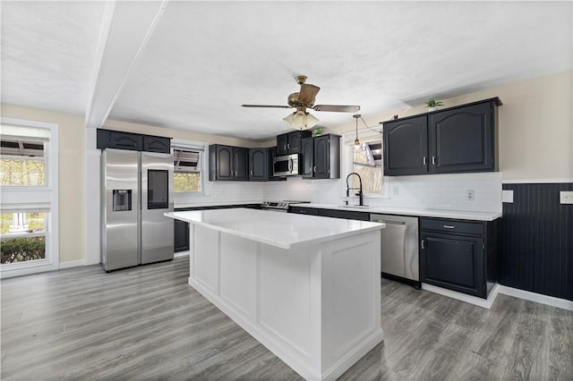 kitchen featuring appliances with stainless steel finishes, light countertops, a kitchen island, and light wood-style flooring