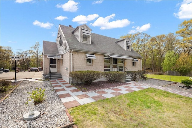 view of front of house featuring entry steps, brick siding, and a front lawn