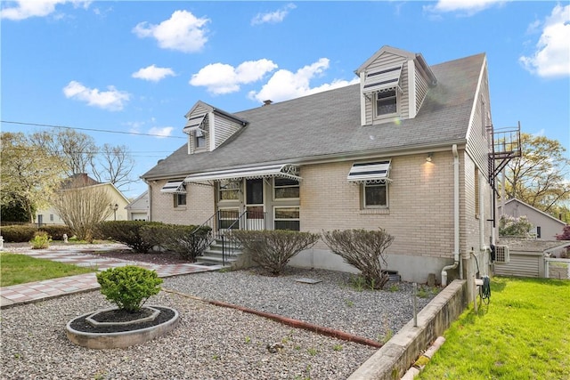 cape cod home featuring brick siding and a front yard