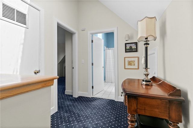 corridor featuring dark carpet and lofted ceiling