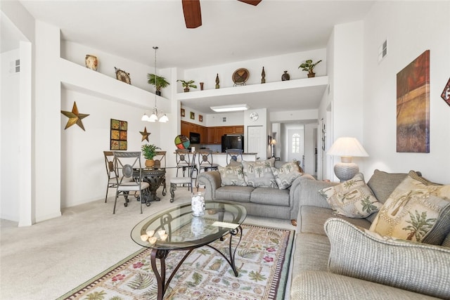 living room featuring ceiling fan with notable chandelier and light carpet