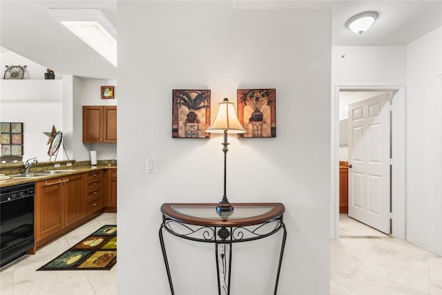 kitchen with light stone countertops, black dishwasher, and sink