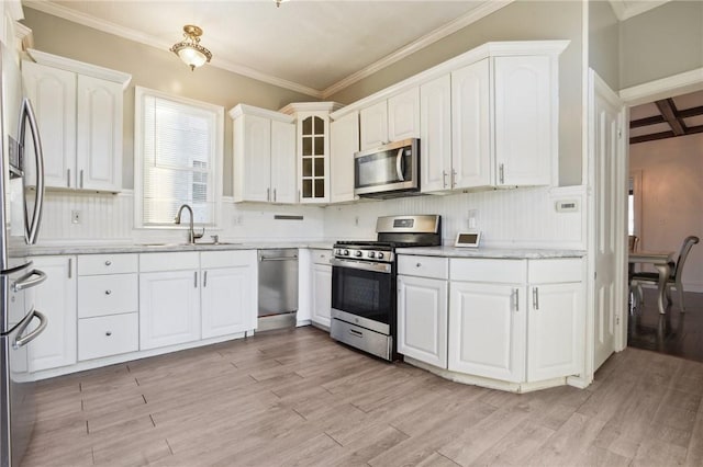 kitchen featuring stainless steel appliances, light hardwood / wood-style flooring, crown molding, and sink