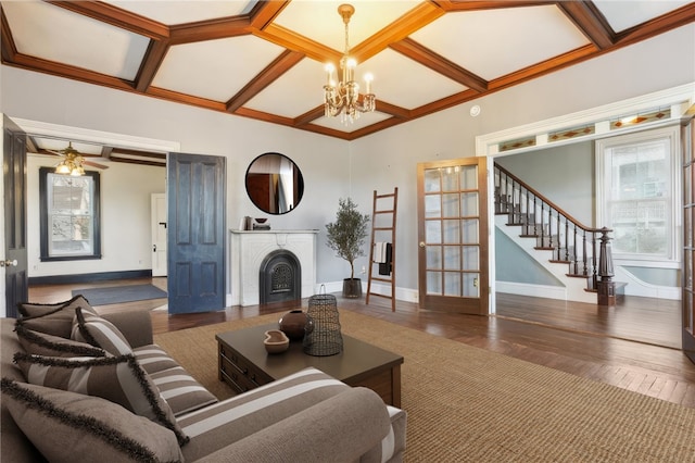 living room with ornamental molding, ceiling fan with notable chandelier, dark wood-type flooring, and coffered ceiling