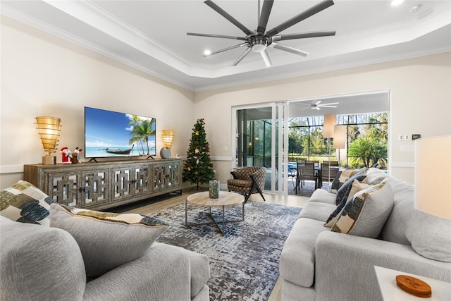 living room featuring hardwood / wood-style flooring, ceiling fan, a raised ceiling, and ornamental molding