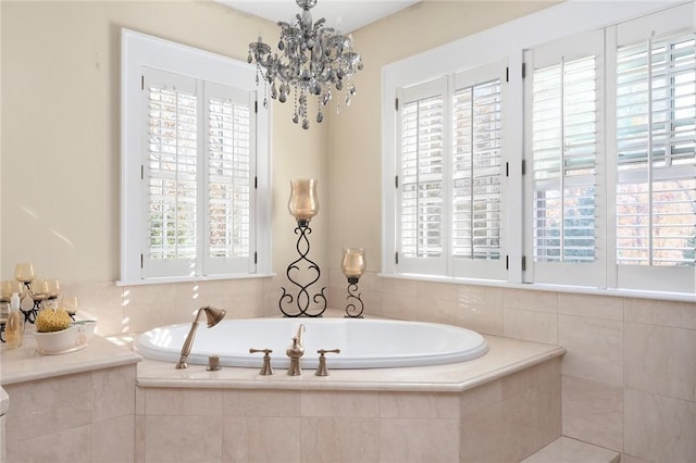 bathroom with a relaxing tiled tub, a wealth of natural light, and a chandelier