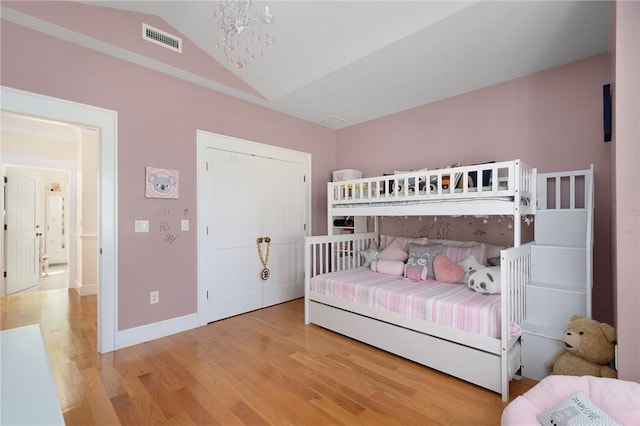 bedroom featuring hardwood / wood-style floors, an inviting chandelier, and lofted ceiling