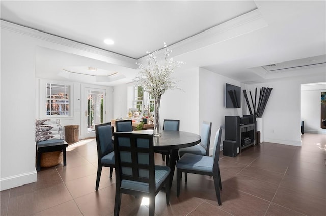 dining area with a tray ceiling, tile patterned floors, and crown molding