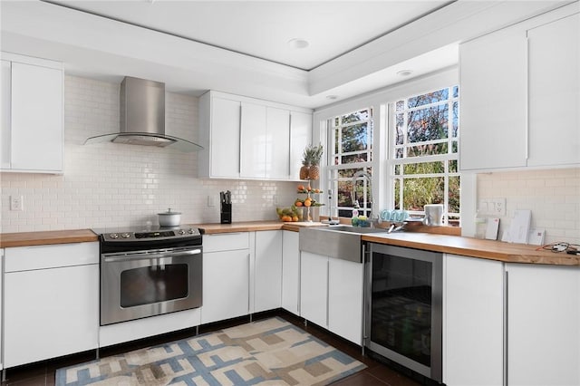 kitchen featuring stainless steel range with electric stovetop, wooden counters, wine cooler, wall chimney exhaust hood, and white cabinetry