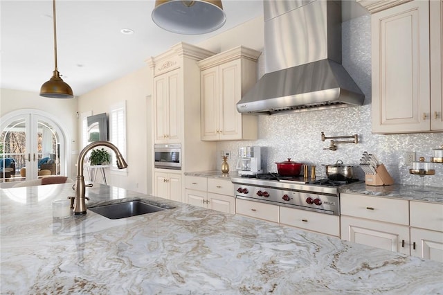 kitchen with french doors, wall chimney exhaust hood, sink, pendant lighting, and stainless steel gas stovetop