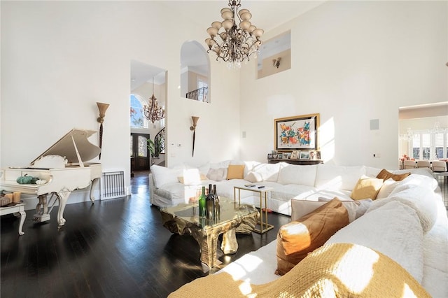 living room featuring wood-type flooring, a high ceiling, and an inviting chandelier