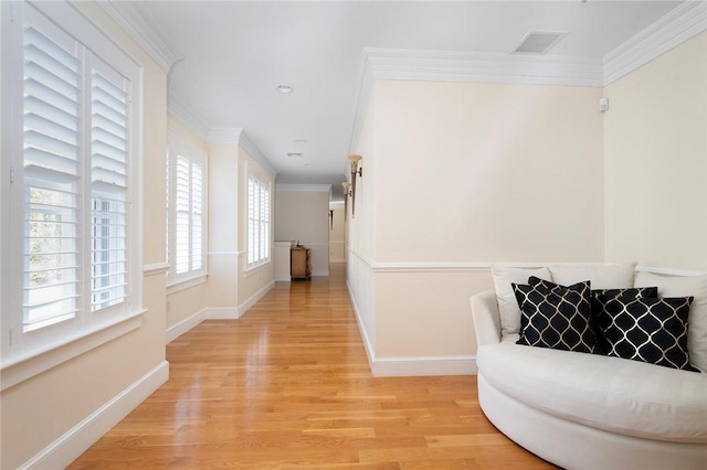 hallway with a healthy amount of sunlight, light wood-type flooring, and crown molding