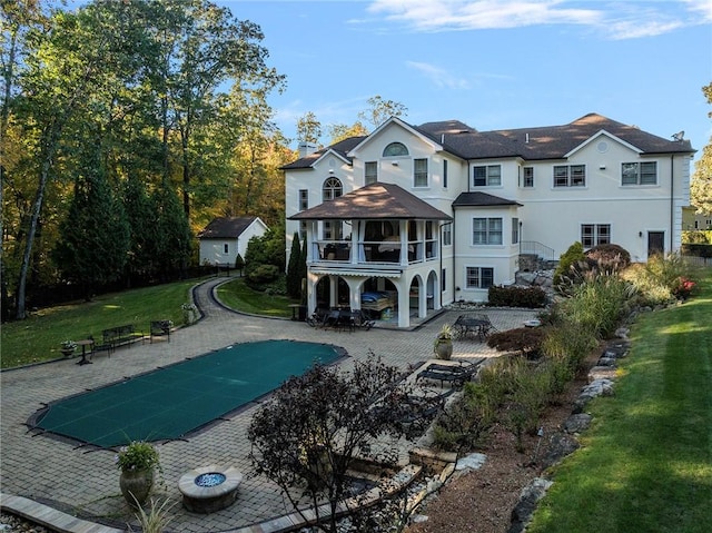 rear view of property featuring a lawn, a patio, and a covered pool