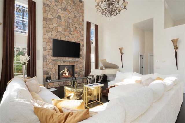 living room with a towering ceiling, a stone fireplace, and a notable chandelier