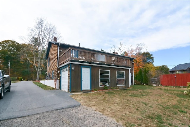 view of front of home featuring a garage, a balcony, and a front lawn