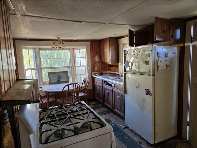 kitchen featuring white appliances, a notable chandelier, and wood walls