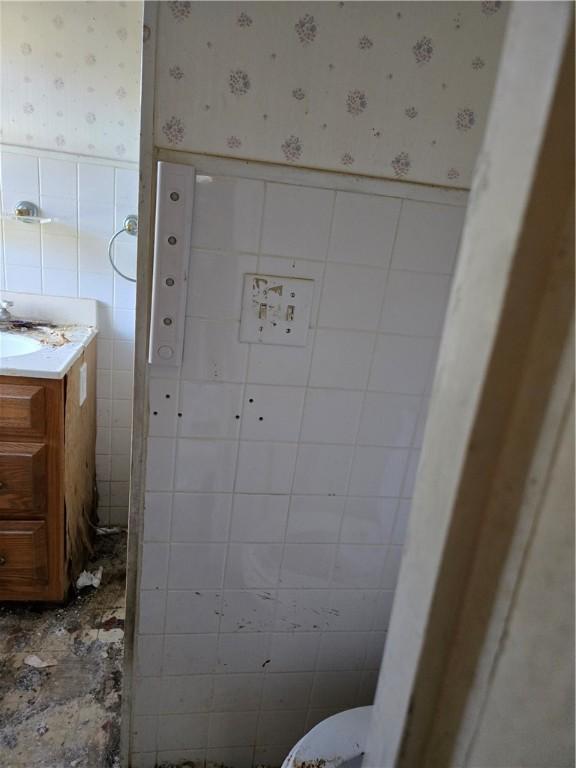 bathroom with vanity, tile walls, and toilet