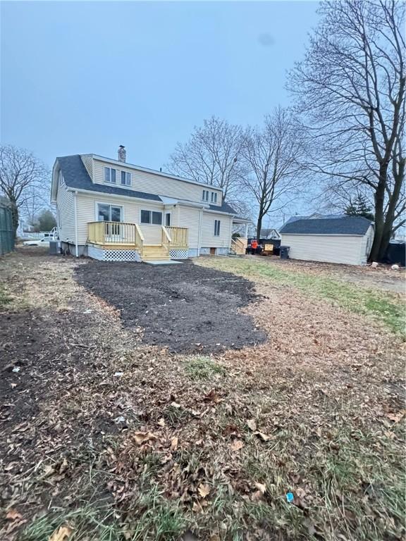 back of house featuring a deck and a storage shed