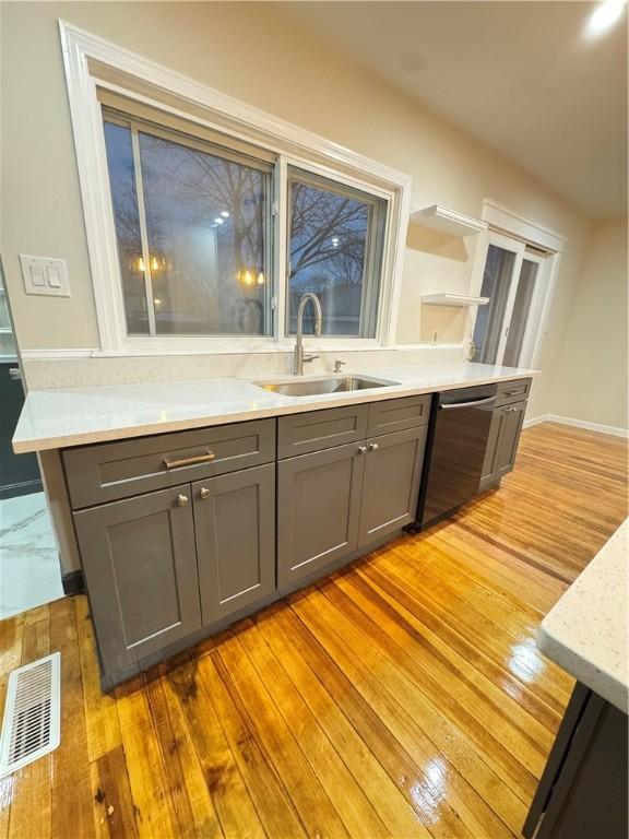 kitchen with dishwasher, gray cabinets, light hardwood / wood-style floors, and sink