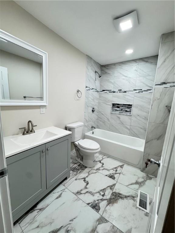 full bathroom featuring vanity, tiled shower / bath combo, and toilet