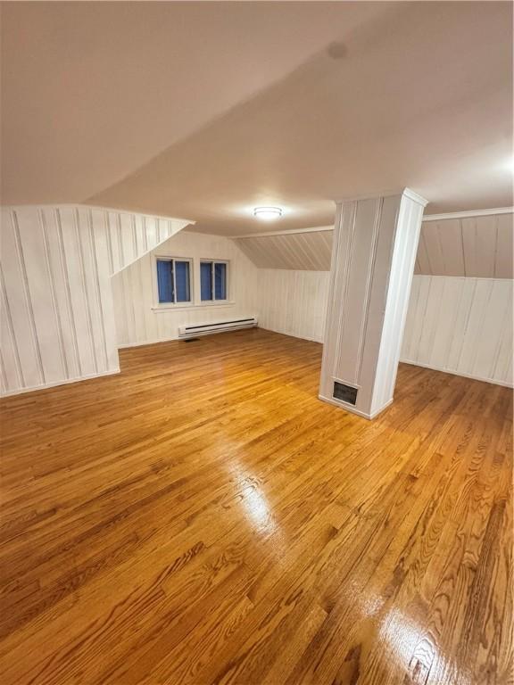 bonus room featuring a baseboard heating unit, lofted ceiling, and light hardwood / wood-style flooring