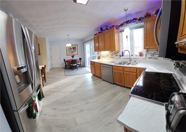 kitchen with a wealth of natural light, light hardwood / wood-style floors, decorative light fixtures, and appliances with stainless steel finishes