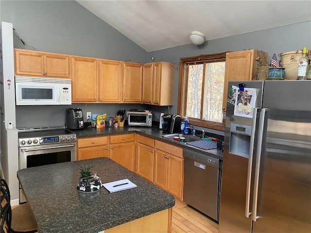 kitchen with stainless steel appliances, sink, light hardwood / wood-style floors, a kitchen island, and lofted ceiling