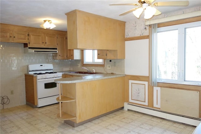 kitchen with gas range gas stove, sink, ceiling fan, baseboard heating, and kitchen peninsula