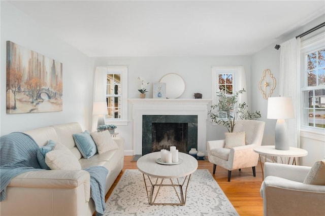 living room featuring a high end fireplace, light wood-type flooring, and a wealth of natural light