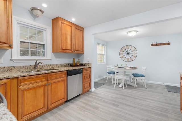 kitchen featuring light stone countertops, sink, stainless steel dishwasher, and light hardwood / wood-style flooring