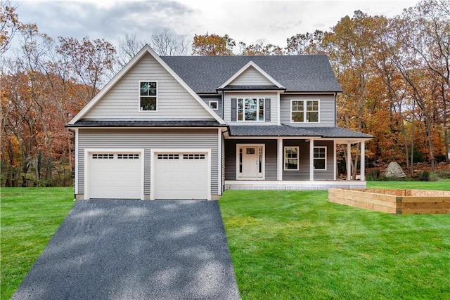 view of front of home featuring a porch, a garage, and a front lawn