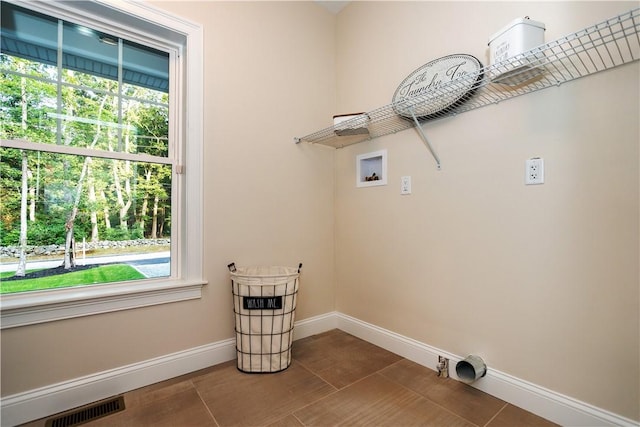 clothes washing area with washer hookup, electric dryer hookup, and dark tile patterned flooring