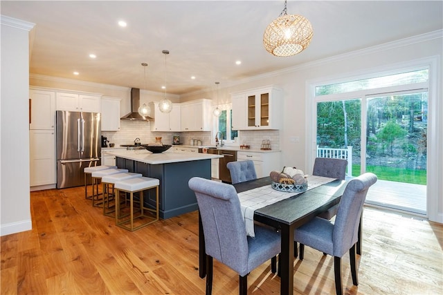 dining room with light hardwood / wood-style floors, ornamental molding, and sink