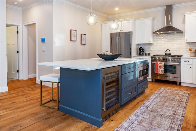 kitchen featuring white cabinets, high end appliances, beverage cooler, and wall chimney range hood