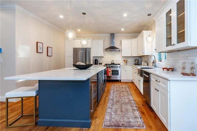 kitchen with wall chimney exhaust hood, a center island, high end appliances, and decorative light fixtures