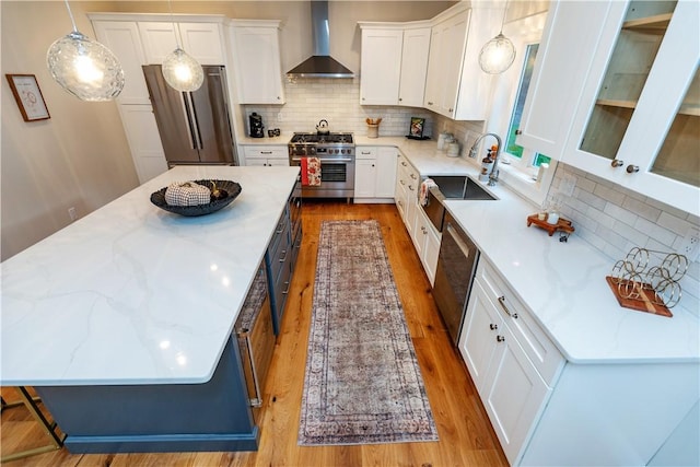 kitchen featuring white cabinetry, a kitchen island, wall chimney exhaust hood, and appliances with stainless steel finishes