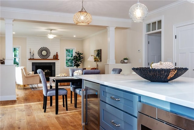 kitchen with ceiling fan, a tile fireplace, pendant lighting, light hardwood / wood-style floors, and wine cooler