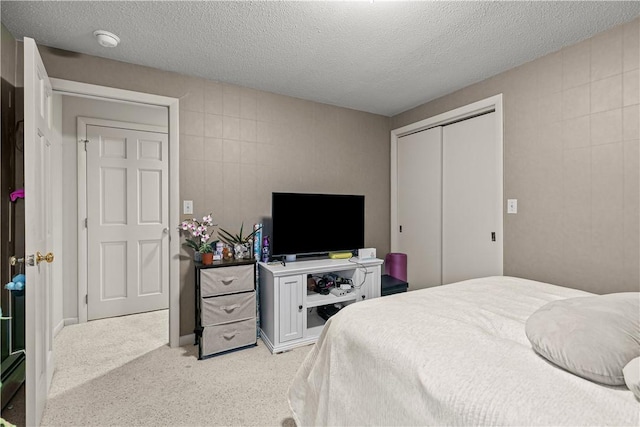 bedroom featuring a closet, light colored carpet, and a textured ceiling