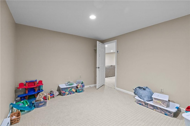 recreation room with carpet floors and a baseboard heating unit