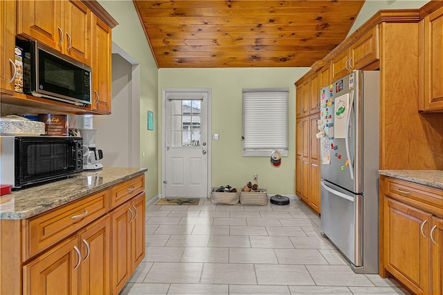 kitchen featuring wood ceiling, light stone countertops, stainless steel refrigerator, and vaulted ceiling