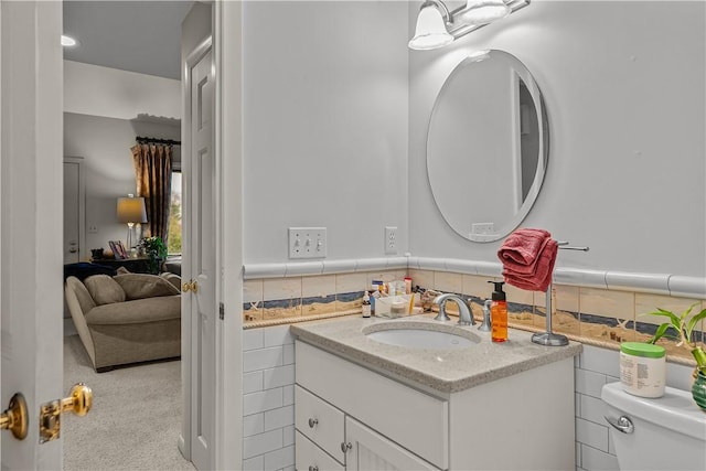 bathroom with vanity, toilet, and tile walls