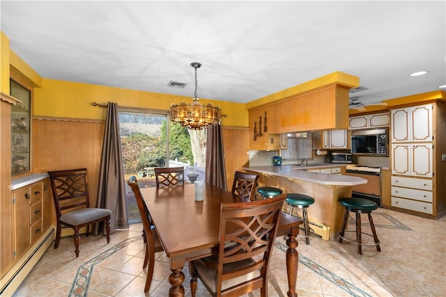 tiled dining area with ceiling fan with notable chandelier, a baseboard heating unit, and sink