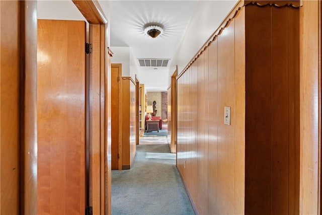 corridor featuring light carpet and wooden walls